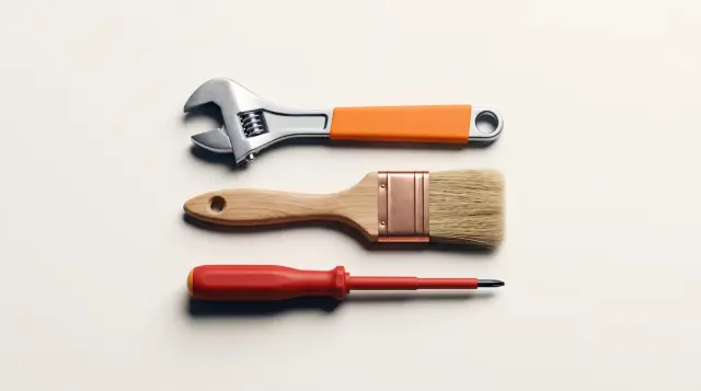 A neat arrangement of a spanner, paintbrush and screwdriver on warm paper